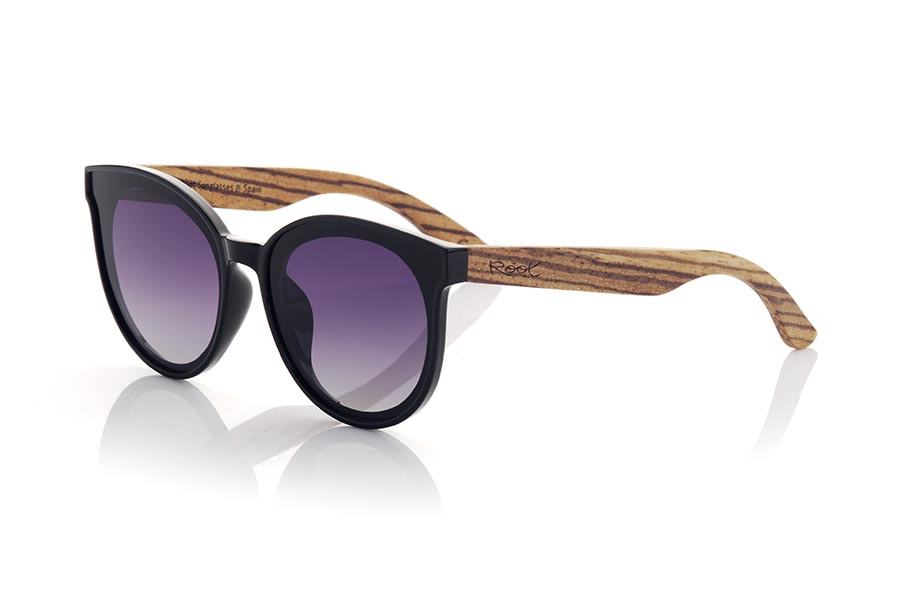 Wood eyewear of Walnut SOPHIA. Sophia sunglasses are the perfect accessory to add a touch of style to your looks at all times. With a rounded frame in satin black, the lenses are mounted on the frame, giving it a retro and modern touch at the same time. The wide temples in grained walnut make a harmonious contrast to the frame. This model is a very attractive female model, although some more daring men will also want to have one. It is available in two lens colors so you can choose the one that best suits your needs and style. Do not hesitate to get some Sophia glasses to protect your eyes from the sun with style. Front measurement approx: 142x55mm for Wholesale & Retail | Root Sunglasses® 